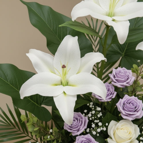 Close-up of handcrafted white lily, lavender rose, and greenery details in a luxury funeral spray arrangement.